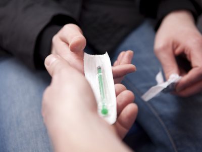 A drug worker giving a service user clean hypodermic needles and syringes