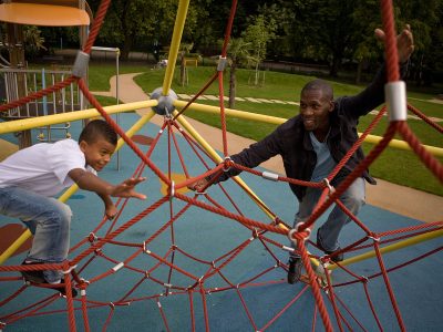 A child and father playing outdoors in a playground