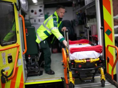 An empty trolley is wheeled onto an ambulance