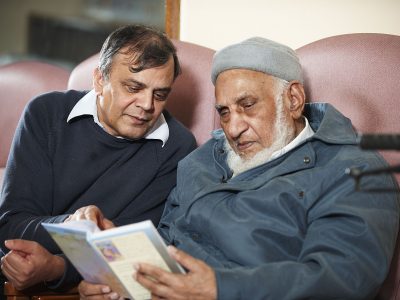 An older man reading with a carer