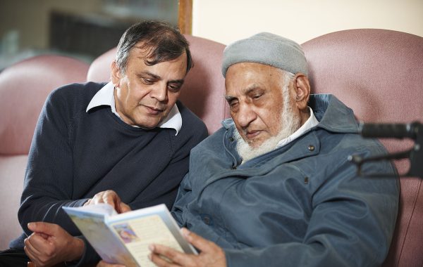 An older man reading with a carer