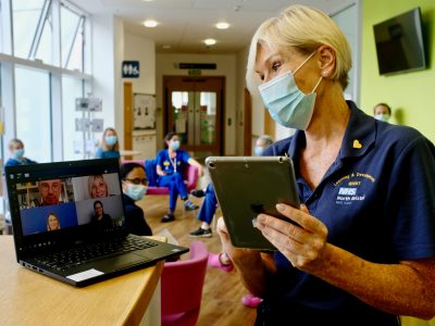 An NHS worker in a face mask during an online meeting