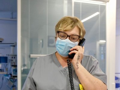 An NHS worker in a face mask on a phone call