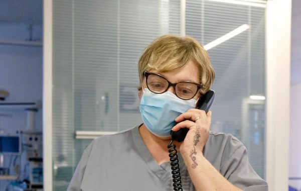 An NHS worker in a face mask on a phone call