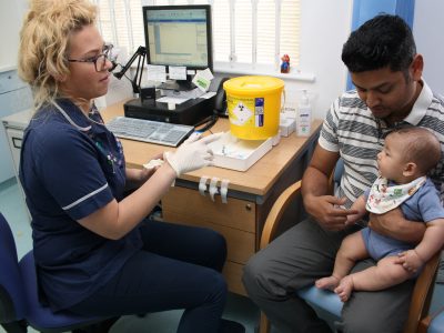 A primary care nurse with a father and baby