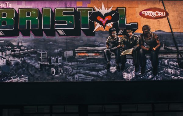 Street art showing the Bristol skyline with three young people sitting in front of it