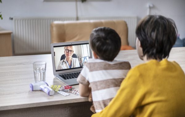 A child and parent on a video call with a doctor