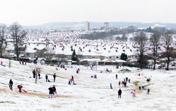 A snowy scene in Bristol, with families playing in a park