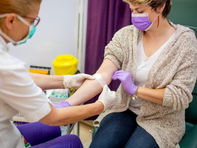 A nurse applies a plaster to a patient's arm following a blood test
