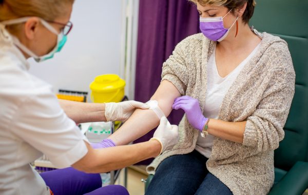 A nurse applies a plaster to a patient's arm following a blood test