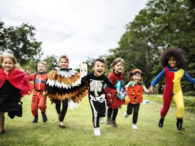 Children in Halloween costumes running around outside