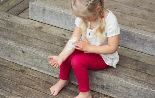 A little girl applies moisturiser to her arm