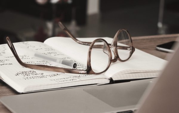 A pair of glasses has been abandoned on a notebook filled with notes