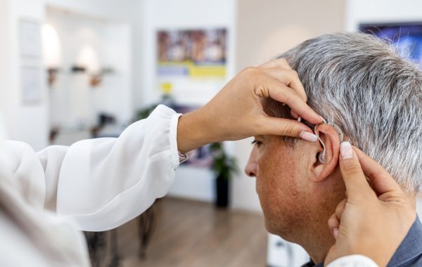 A man is being fitted with a hearing aid at an audiology clinic