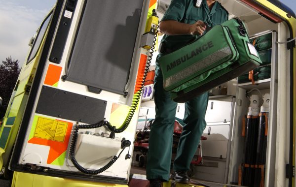 A paramedic leaves the back of an ambulance with an equipment bag