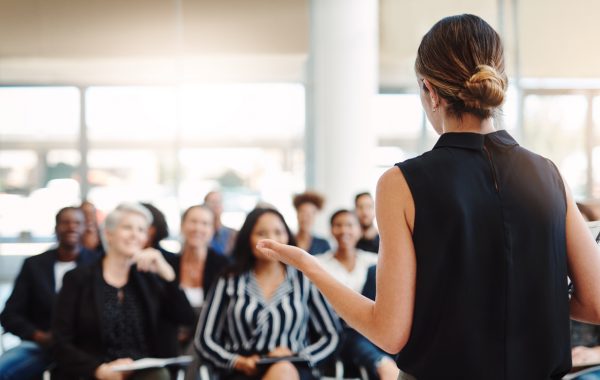 A young woman is delivering a speech during a conference.