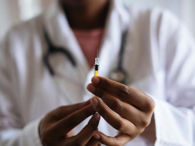 Close up view of healthcare professionals hands as they hold a filled syringe