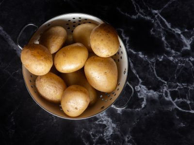Potatoes in a colander on a marble worktop