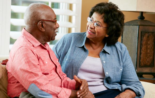 An older couple sitting together on a sofa, chatting and smiling with each other