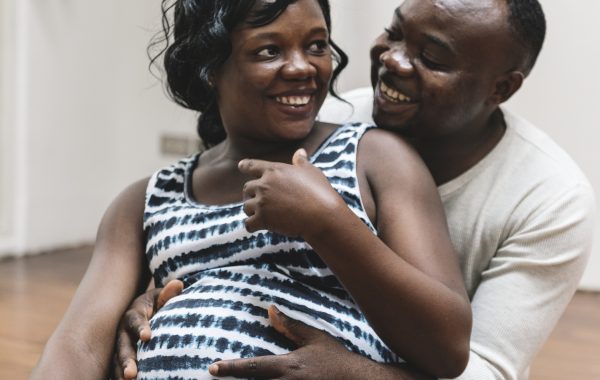 A Black pregnant woman laughs with her partner