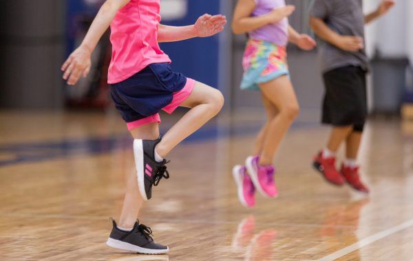 Young children do cardio exercises in school gym
