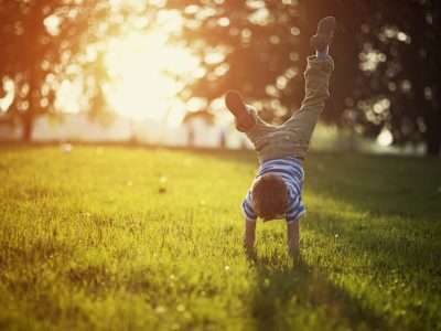 A little boy is doing a handstand on some grass