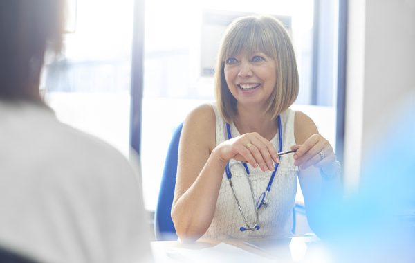 A doctor wearing a lanyard talks to a patient