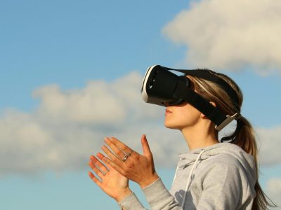 A young woman is wearing a virtual reality headset outdoors