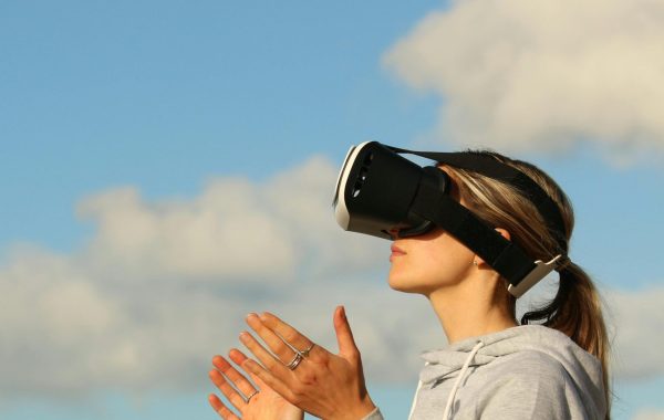 A young woman is wearing a virtual reality headset outdoors