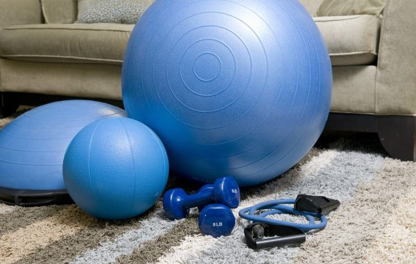 A set of home exercise equipment is laid out in front of the sofa