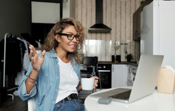 A woman is taking part in an online webinar while sitting at her kitchen table