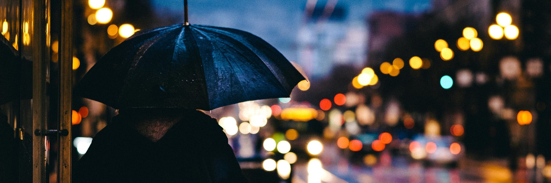 A person holding an umbrella walking along a city street