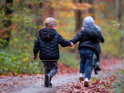 Two young children holding hands and running away from the camera