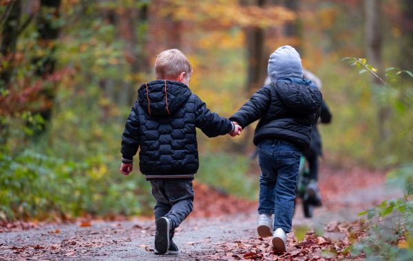 Two young children holding hands and running away from the camera