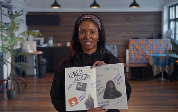 Screenshot from the video, with a participant holding up her zine to the camera