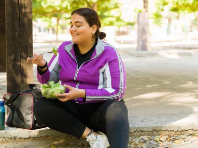 A woman in active wear eats a salad