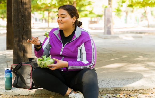 A woman in active wear eats a salad